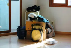 Umzugkartons mit Rucksäcken zusammengestellt in einer Ecke
