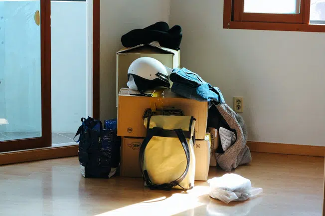 Umzugkartons mit Rucksäcken zusammengestellt in einer Ecke