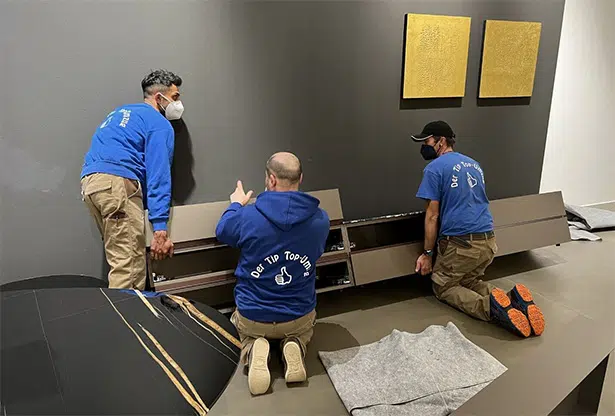 Mitarbeiter der Tip Top GmbH verpacken ein Regal