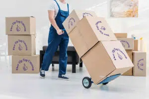 Ein Mitarbeiter der Umzugsfirma Tip Top Umzug GmbH transportiert Umzugskartons mit einem Hubwagen