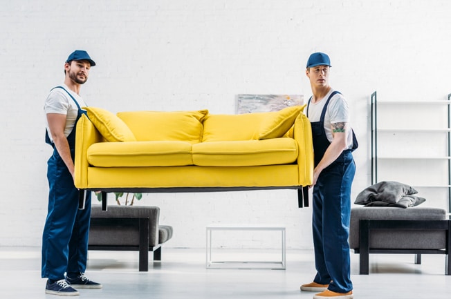 Zwei Umzugsmitarbeiter tragen eine Couch