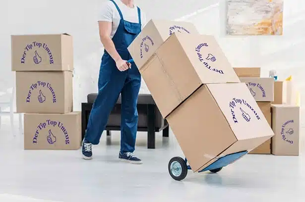 Ein Mitarbeiter der Umzugsfirma Tip Top Umzug GmbH transportiert Umzugskartons mit einem Hubwagen in Freising