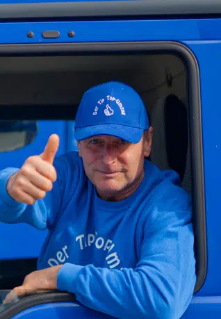 Ein Mann der aus dem Lkw Fenster schaut und den Daumen hochhebt