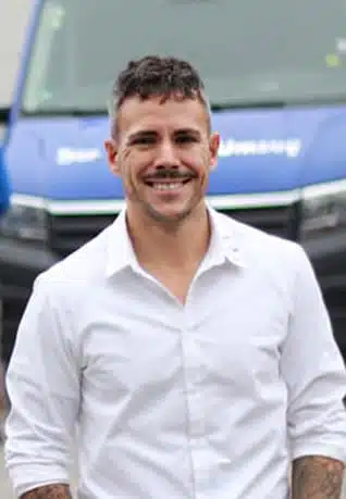 Mann mit weißem Hemd vor blauem Lkw